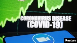FILE - Zoom logo is seen in front of diplayed coronavirus disease (COVID-19) in this illustration taken March 19, 2020. 