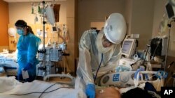 FILE - Dr. Rafik Abdou checks on a COVID-19 patient at Providence Holy Cross Medical Center in the Mission Hills section of Los Angeles.