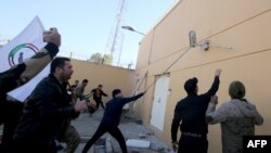 伊拉克示威者冲击美国驻巴格达大使馆的外墙，抗议者谴责美国对伊拉克境内伊朗支持的民兵发动空袭。 2019年12月31日，法新社照片）