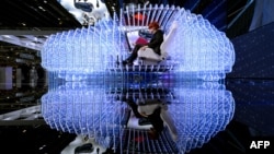 A woman poses inside the mockup of a car at the Opel booth during the press day of the Geneva Car Show on March 3, 2015 in Geneva. The show runs through March 5 - 15, 2015. AFP PHOTO / FABRICE COFFRINI