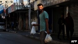 Palestinac prelazi ulicu nakon što je nabavio hranu za svoju porodicu u Kan Junisu, južnom pojasu Gaze, 14. oktobra 2023. godine