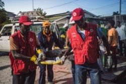 Red Cross paramedics carry a girl injured during a 7.2 magnitude earthquake in Les Cayes, Haiti, Aug. 14, 2021.