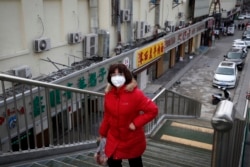 A woman wearing a protective face mask walks past closed restaurants amid a coronavirus outbreak, in Beijing, March 2, 2020.