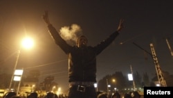 An anti-Morsi protester smokes a cigarette and and gestures in front of members of the Republican Guard blocking a road to the presidential palace in Cairo, Egypt, December 6, 2012. 