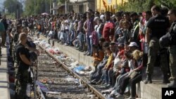 Police officers secure the railway tracks before a train that would take the migrants towards Serbia enters the railway station in the southern Macedonian town of Gevgelija, Aug. 23, 2015. 