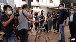 Pro-democracy legislator Ted Hui, second from right, is surrounded by photographers outside a police station after being released in Hong Kong, Nov. 18, 2020.