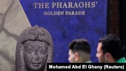 Dua orang pria melewati poster parade emas firaun setelah renovasi Lapangan Tahrir untuk memindahkan 22 mumi dari Museum Mesir di Tahrir ke Museum Nasional Peradaban Mesir di Fustat, di Kairo, Mesir, 1 April , 2021. (Foto: REUTERS/Mohamed Abd El Ghany)