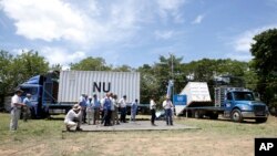 Colombia's President Juan Manuel Santos, right, talks with U.N. observers in front of containers holding weapons once carried by guerrillas of the Revolutionary Armed Forces of Colombia, FARC, at a demobilization site in Fonseca, Aug. 15, 2017. 