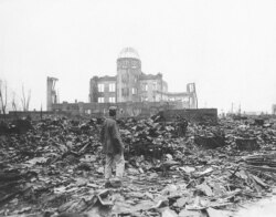 FILE - In this 1945 file photo, an Allied war correspondent stands in the ruins of Hiroshima, Japan, just weeks after the city was leveled by an atomic bomb.