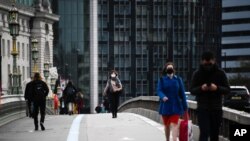 People wearing face masks walk across Westminster Bridge, in London, Britain, Oct. 7, 2020.
