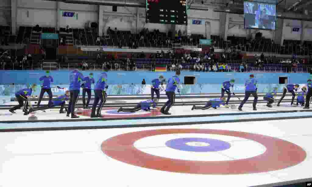 This multiple exposure photo shows the Sweden curling team throwing during a round robin session against China in the Ice Cube Curling Center at the 2014 Winter Olympics, Feb. 14, 2014.