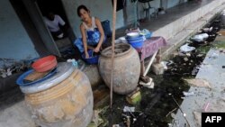 A Burmese migrant washes dishes outside her room at an apartment building housing Burmese migrant workers in Mahachai, an industrial area south of Bangkok, August 25, 2010.
