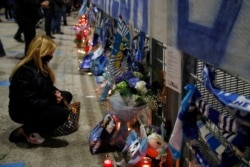 A woman pays her respects to soccer legend Diego Maradona outside the San Paolo Stadium, in Naples, Italy, Nov. 25, 2020.