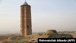 Sebuah tank Rusia yang hancur tampak di dekat satu dari dua menara masjid yang dibangun pada abad ke-12 di kota Ghazni, 16 Juli 2013 (foto: Rahmatullah Alizada/AFP)