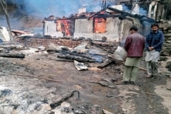 Local residents stand beside a burning house following cross-border shelling between Pakistani and Indian forces in Tehjain village at the Line of Control in Neelum Valley, Pakistan-administered Kashmir, Nov. 13, 2020.