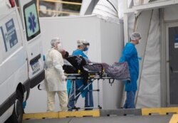 A patient with symptoms related to COVID-19 is brought to a field hospital by workers in full protective gear in Leblon, Rio de Janeiro, Brazil, June 4, 2020.