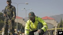 Official picks up pieces of flesh belonging to suicide attacker outside Pakistani naval headquarters in Islamabad, 2 Dec 2009