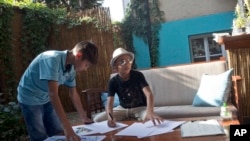 Farhad Nouri, center, signs copies of his work at an art exhibition in Belgrade, Serbia, Aug. 9, 2017.