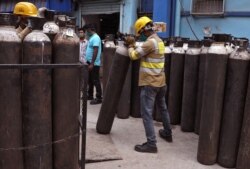 Workers load empty oxygen cylinders onto a supply truck for refilling, at the Medical College and Hospital, amid the spread of the coronavirus disease (COVID-19), in Kolkata, India, May 5, 2021.