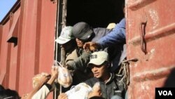 Warga membagikan makanan untuk para pekerja dari Pharkat, wilayah pertambangan terbesar di Burma, di stasiun Kwalin (15/1). Ratusan pekerja tambang pulang mudik karena adanya konflik pemerintah dan tentara independen Kachin (KIA).