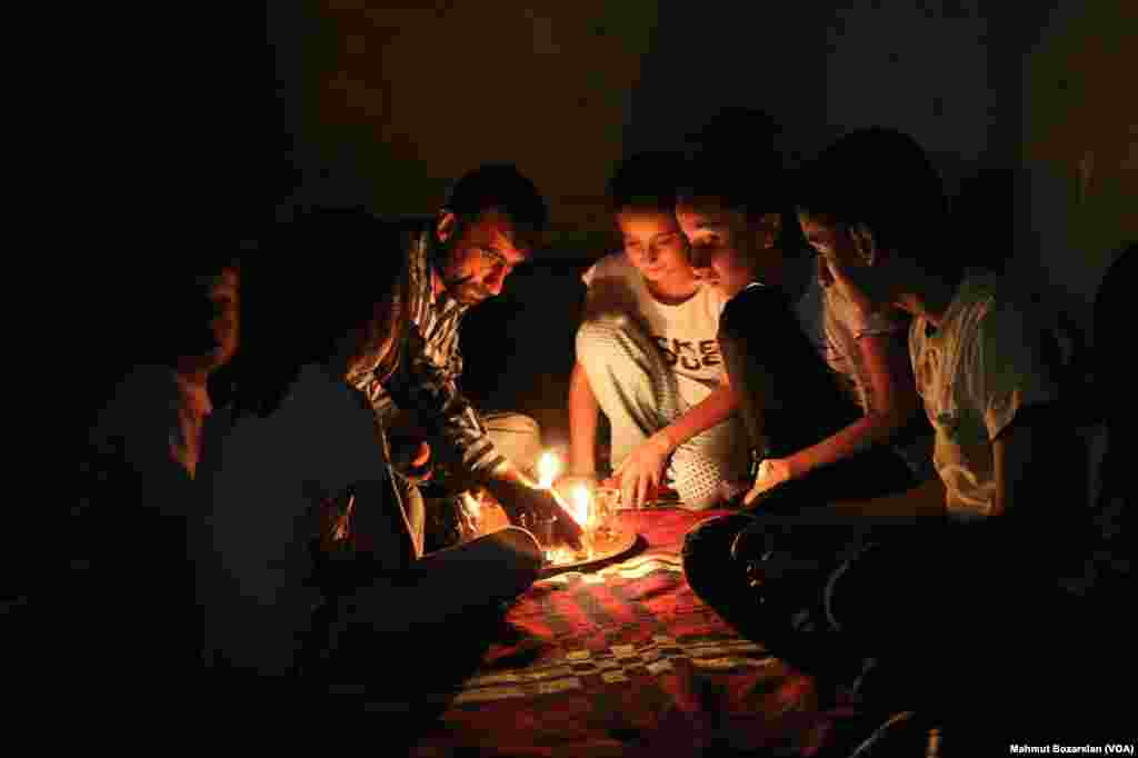 The government has cut power and water to Sur, in Diyarbakir, Turkey, as efforts are made to rebuild it. A family reads by the light of candles inside their home.