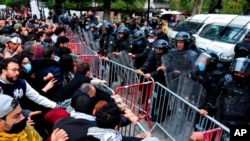 Demonstrators face police in Tunis, Jan. 23, 2021. Tunisia is extending its virus curfew and banning demonstrations as it tries to stem a rapid rise in infections and calm tensions after a week of protests over economic problems.