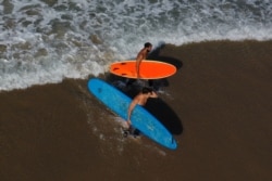 Surfers walk out of the Pacific Ocean on the first day of a record heat wave, amid the global outbreak of coronavirus disease, in Hermosa Beach, near Los Angeles, Calif., Sept. 4, 2020.