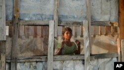 A Rohingya refugee girl looks through a mesh window at a camp set up for the refugees on the outskirts of Jammu, India, Aug. 16, 2017.