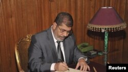 Misr prezidenti Muhammad Mursiy yangi konstitutsiyani kuchga kiritish haqida qaror imzolamoqda, 25-dekabr, 2012-yil