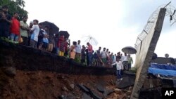Regu penyelamat dan masyarakat sekitar berdiri di dekat tembok yang runtuh di Mumbai, India, 2 Juli 2019.