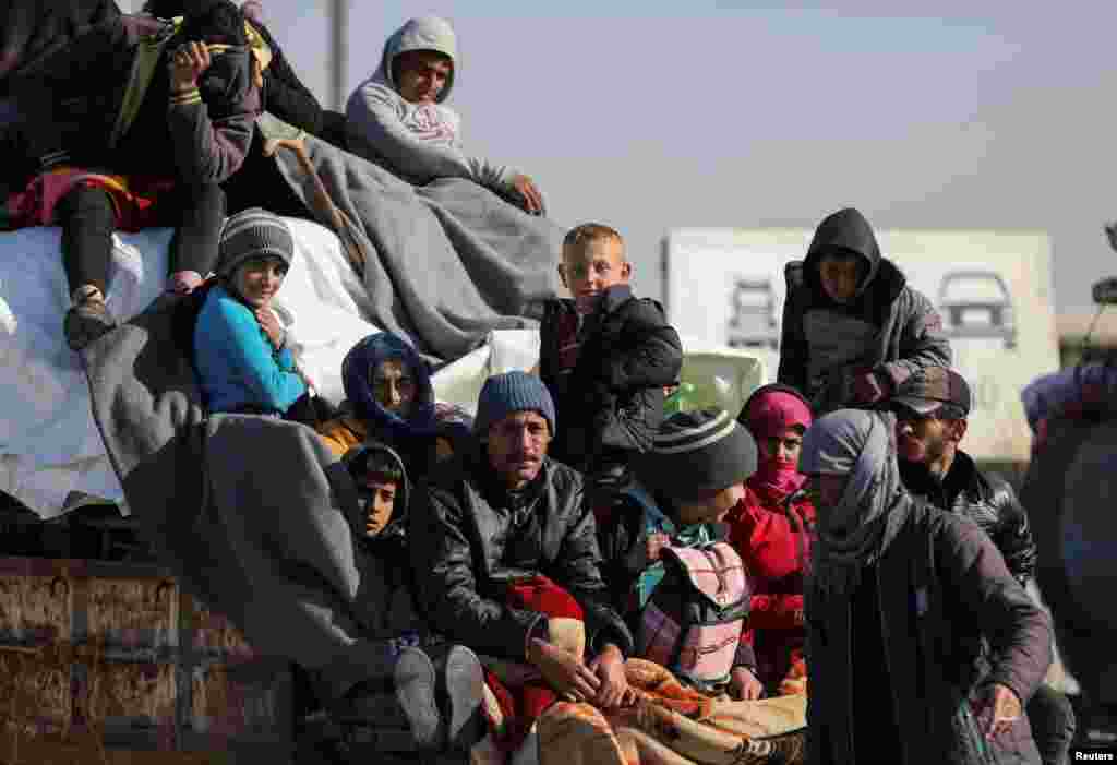Displaced people who fled from Aleppo countryside, sit together on the back of a truck in Tabqa, Syria, Dec. 3, 2024.