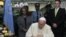 With Achim Steiner, executive director of the U.N. Environment Program, right, looking on, Pope Francis signs the visitors book at the United Nations regional office in Nairobi, Kenya, Nov. 26, 2015.