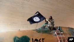FILE - A fighter of the Islamic State group waving their flag.