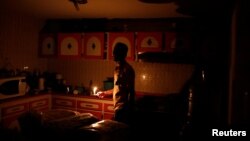 Americo Fernandez uses a candle to illuminate the kitchen at his home during a blackout in Maracaibo, Venezuela, July 25, 2018. 