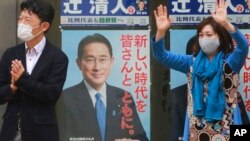 A supporter of Japan's governing Liberal Democratic Party waves by posters of Japanese Prime Minister Fumio Kishida during a campaign rally for the Oct. 31 lower house elections, in Tokyo, Oct. 27, 2021.