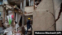 Rodrigo Diaz Mejia, 38, climbs through a crack in the wall into what was a second-story apartment in the Portales Norte neighborhood of Mexico City.