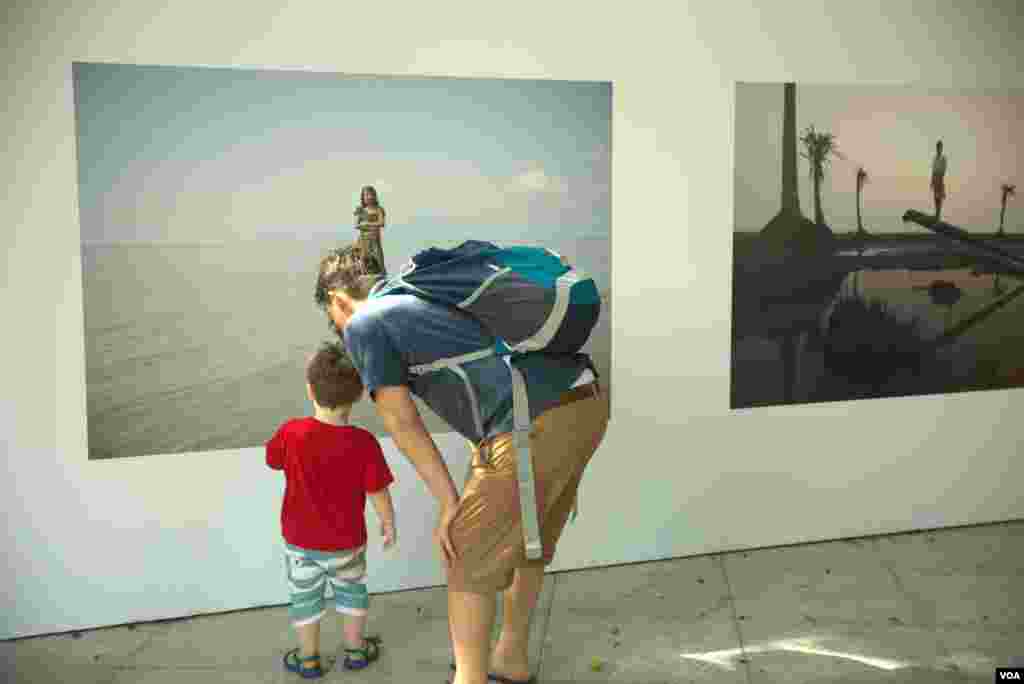 ភ្ញៀវជាតិ​និង​អន្តរជាតិ​កំពុង​មើល​ស្នាដៃ​ថត​រូប​មួយ​​ដែល​ត្រូវ​បាន​ដាក់​បង្ហាញ​នៅ​ក្នុង​វិទ្យាល័យ​ព្រះស៊ីសុវត្ថិ​កាល​ពី​ថ្ងៃទី​០៦ ខែ​តុលា ឆ្នាំ ២០១៨។(ទុំ ម្លិះ/VOA)