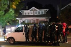 Portland police hang off the side of a riot van while searching for protesters in the Laurelhurst neighborhood after dispersing a crowd of about 200 people from in front of the Multnomah County Sheriff's Office early Aug. 8, 2020.