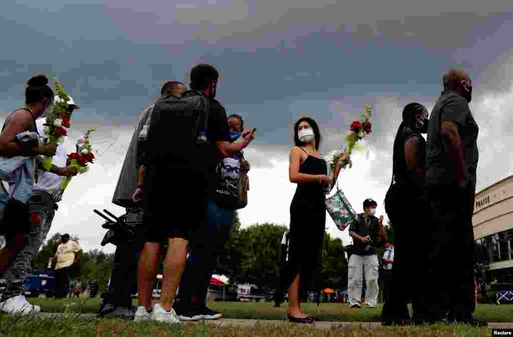 ស្ត្រីម្នាក់កាន់ផ្កា ឈរតម្រង់ជួរ ដើម្បីចូលគោរពវិញ្ញាណក្ខន្ធលោក George Floyd ដែលបានស្លាប់នៅពេលប៉ូលិសឃាត់ខ្លួនលោក នៅព្រះវិហារ Fountain of Praise ក្នុងទីក្រុង Houston រដ្ឋ Texas ថ្ងៃទី៨ ខែមិថុនា ឆ្នាំ២០២០។&nbsp;​