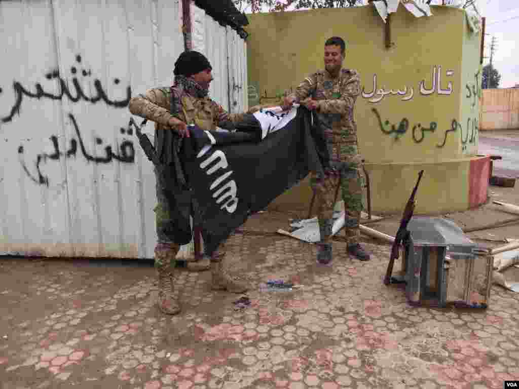 Two Iraqi forces tear IS flag. (Kawa Omar/VOA Kurdish)