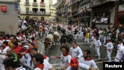 Para pelari mencoba untuk menghindari banteng petarung "Dolores Aguirre" di sudut Estafeta di putaran pertama Festival San Fermin di Pamplona (7/7). Menurut media lokal, satu orang terkena tanduk dan empat lainnya terluka dalam kegiatan lari tahunan yang 