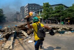 An anti-coup protester throws a Molotov cocktail towards police as they move towards the protest area in Yangon, Myanmar, March 17, 2021.