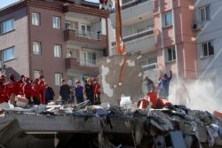 Rescue workers search for survivors at a collapsed building after an earthquake in the Aegean port city of Izmir, Turkey Oct. 31, 2020.
