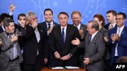 FILE - Brazilian President Jair Bolsonaro, center, is pictured surrounded by parliamentarians during the signing ceremony of the decree that facilitates to own, carry and import weapons, at the Planalto Palace in Brasilia, May 7, 2019. 
