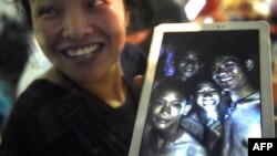 Članica porodice jednog od dečaka pokazuje fotografiju dečaka iz pećine koju su napravili britanski spasioci