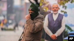 An Indian police officer stands guard near a cutout portrait of Indian Prime Minister Narendra Modi displayed at the main market in Srinagar, Indian-controlled Kashmir, Dec. 11, 2023.