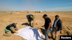 Anggota Pertahanan Sipil Irak membuka penutup kerangka-kerangka dari sebuah kuburan massal yang baru digali di Samawah, kota di barat Irak, 14 April 2019.