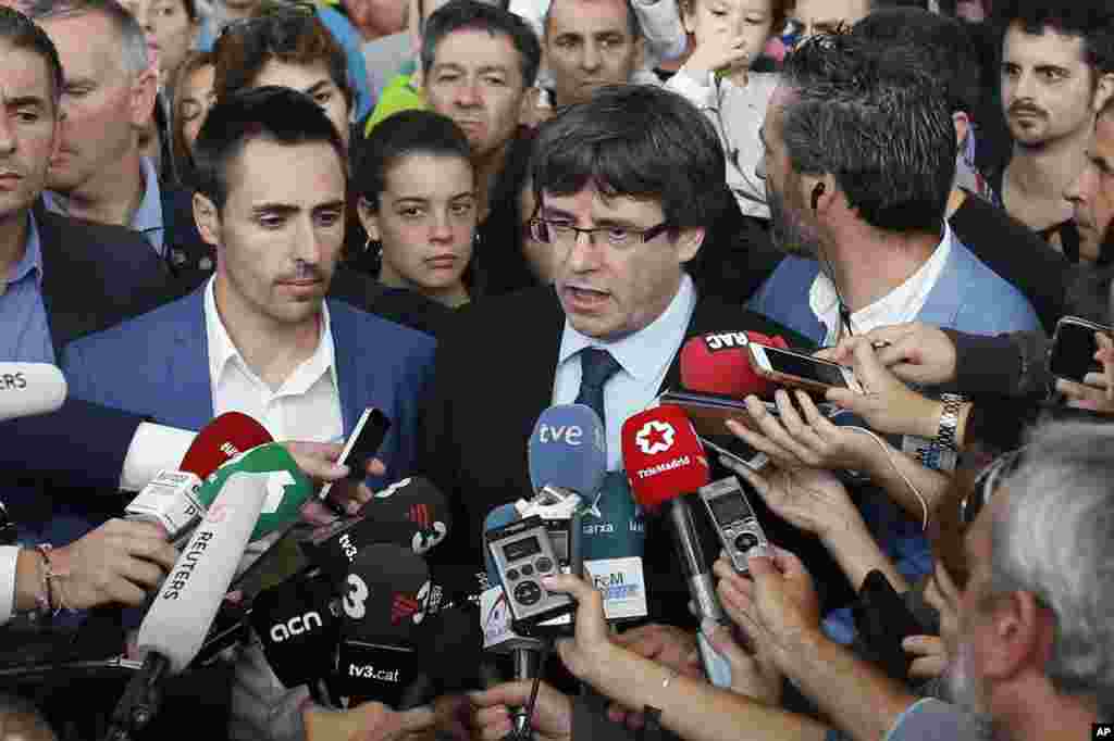 Catalan President Carles Puigdemont, center, speaks to the media at a sports center, assigned to be a polling station by the Catalan government in Sant Julia de Ramis, near Girona, Oct. 1, 2017.