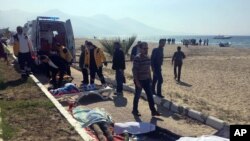 FILE - Turkish rescue workers and medics work next to the bodies of migrants laid out near an ambulance in Kusadasi, Turkey, March 24, 2017.