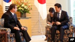 Japanese Prime Minister Shinzo Abe, right, speaks to South Korea's National Intelligence Service Chief Suh Hoon, left, during a meeting in Tokyo Tuesday, March 13, 2018. (Kim Kyung-Hoon/Pool Photo via AP)